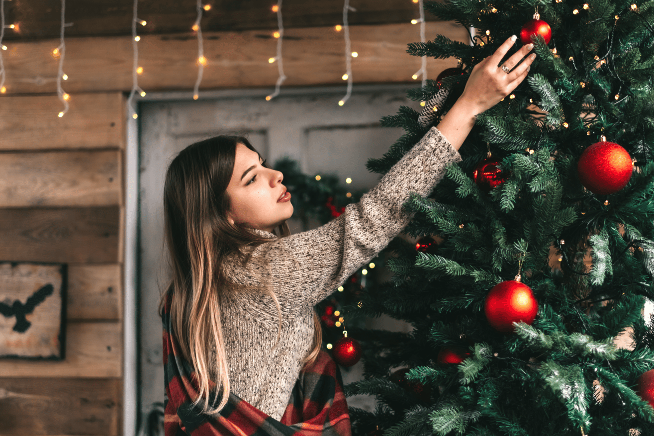 Women experiencing a drop in her mental health during the holidays while putting up a holiday tree