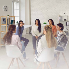 Young women telling their stories in therapy session or support group meeting. Female team talking, sharing news, discussing life situations, giving each other advice, working out solutions together.