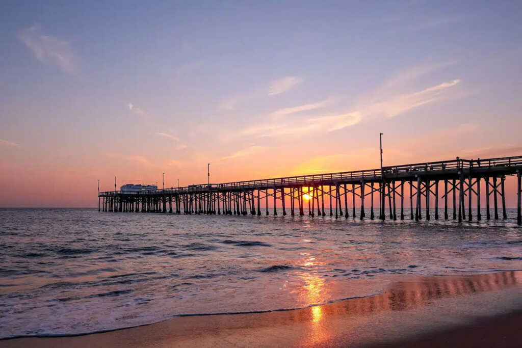 Scenic sunset over the Pacific ocean. A setting sun behind the long pier, Irvine, Orange County, California.